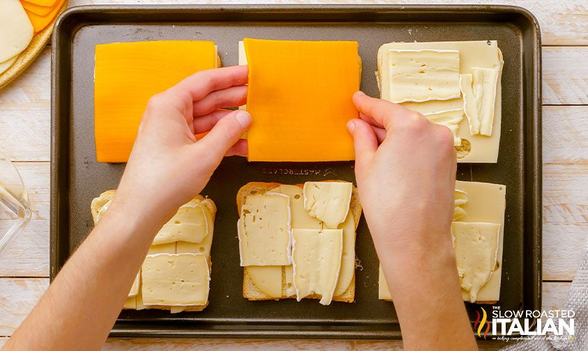 hands assembling grilled cheese for a crowd on sheet pan
