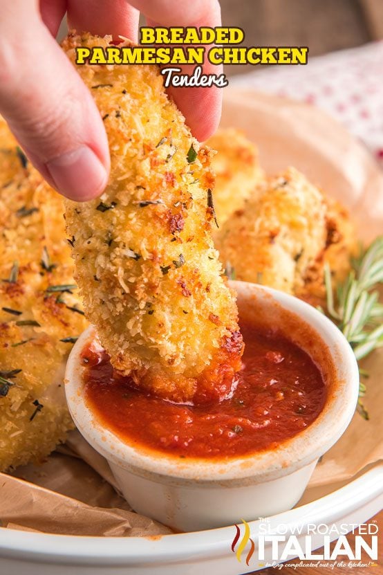 close up of a person dipping parmesan chicken strips into marinara sauce