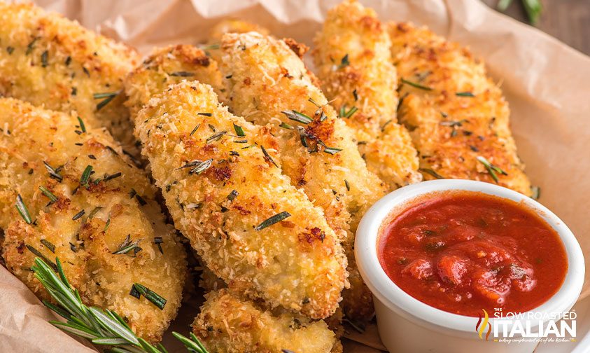 baked breaded chicken fingers on serving tray with bowl of marinara sauce