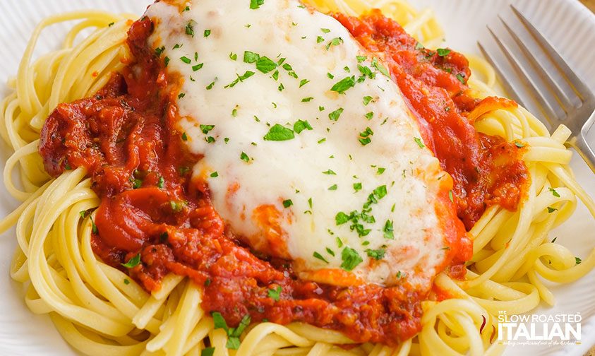 plate of pasta with red sauce and cheesy chicken breast