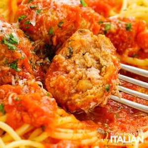 fork piercing a meatball on plate of pasta