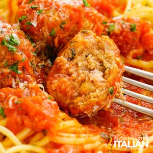 fork piercing a meatball on plate of pasta