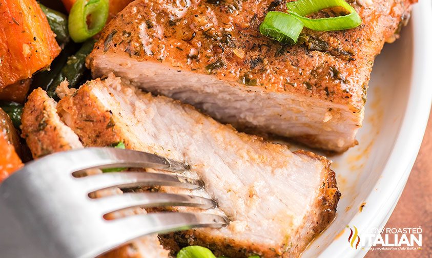 fork piercing slice of baked ranch pork chops