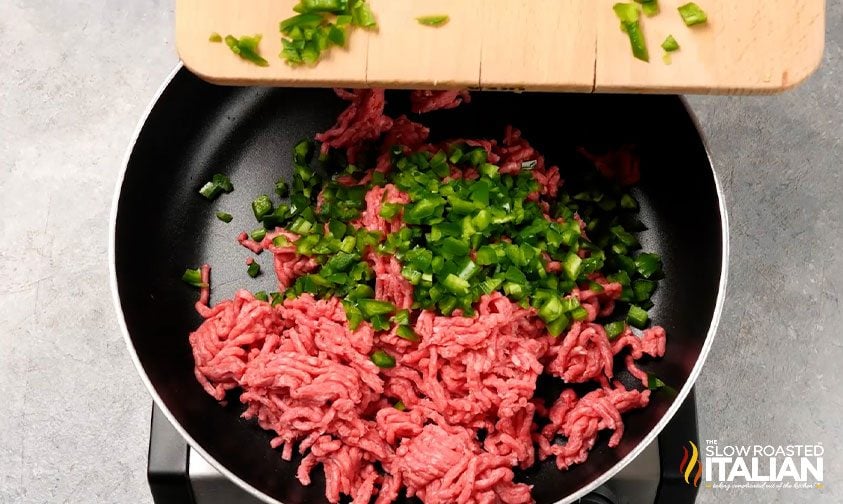 raw ground beef and diced jalapenos in skillet