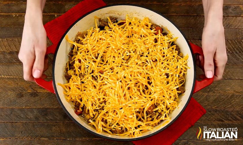 overhead: shredded cheddar cheese over meat in round baking dish