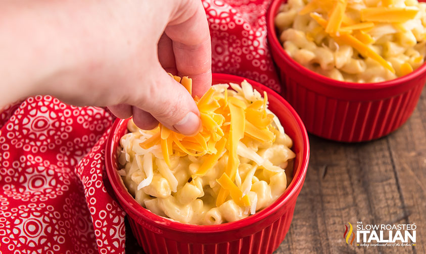 adding shredded cheese to mac and cheese