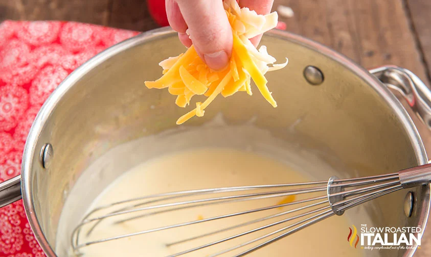 adding shredded cheese to pot