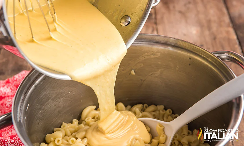 pouring cheese sauce over pasta