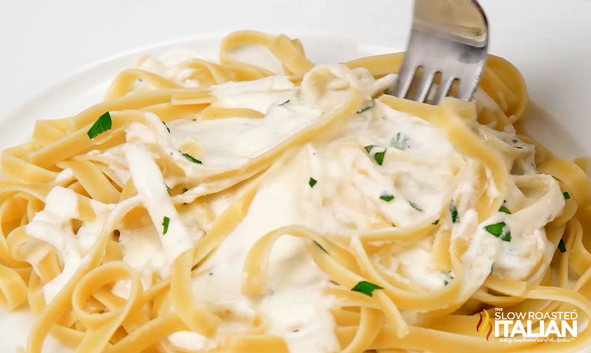 close up fork twirling olive garden cheese sauce into fettucine