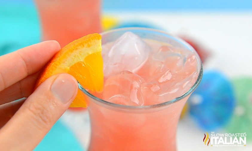 placing orange slice garnish on rim of tropical cocktail glass
