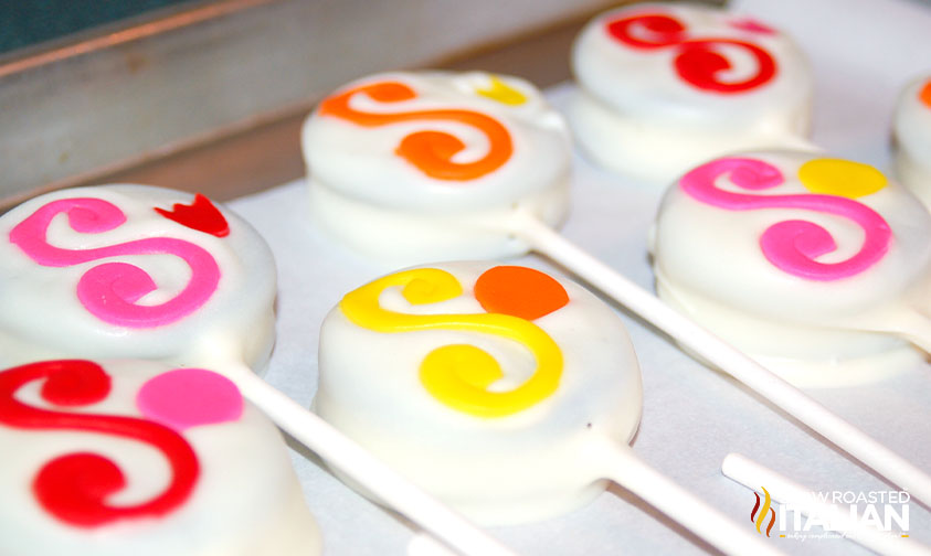 white fondant covered oreo pops decorated with capital letter s in pink frosting