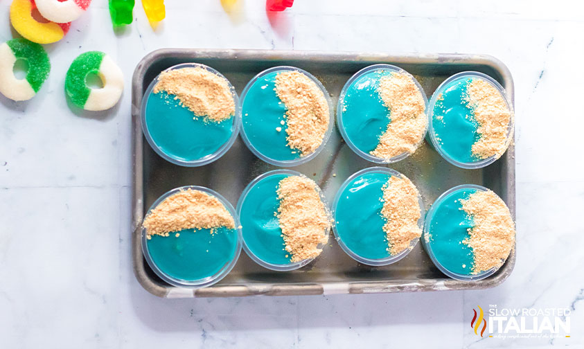 tray of blue pudding shots with graham cracker crumbs on top