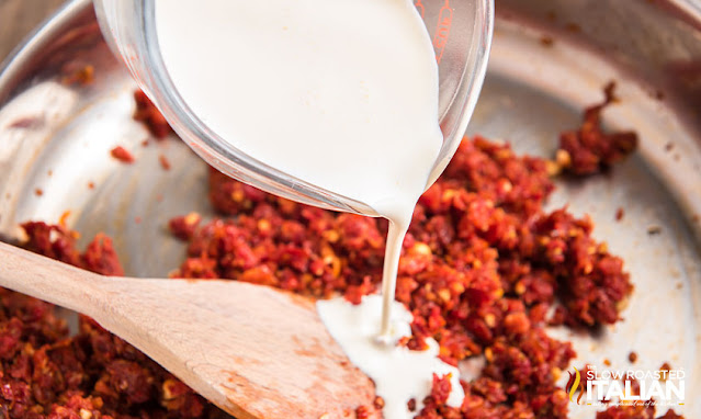 adding heavy cream to skillet of sundried tomatoes