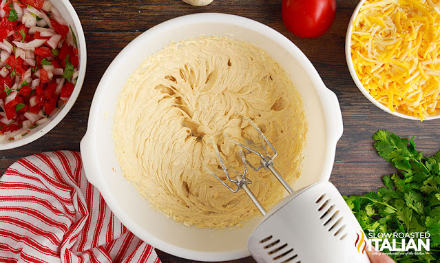hand mixture whipping cream cheese mixture in white mixing bowl