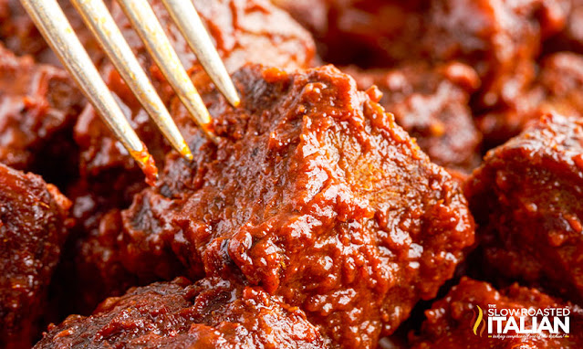 close up: piercing fork into poor man's burnt ends tossed in barbecue sauce