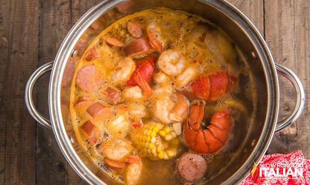 overhead: stock pot simmering with vegetables, lobster tail and shrimp