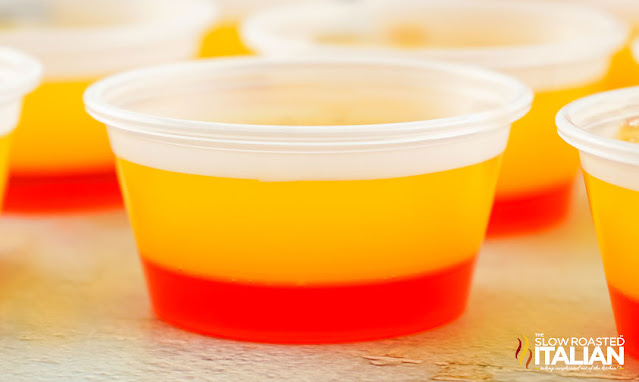 clear plastic cup with layers of orange and strawberry gelatin