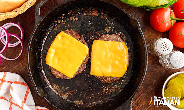 overhead: cheese melting on hamburgers in skillet