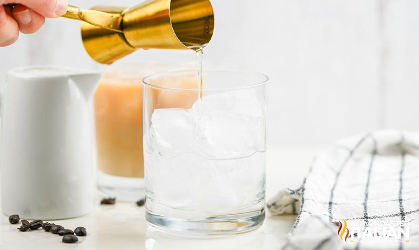 pouring vodka over ice in highball glass