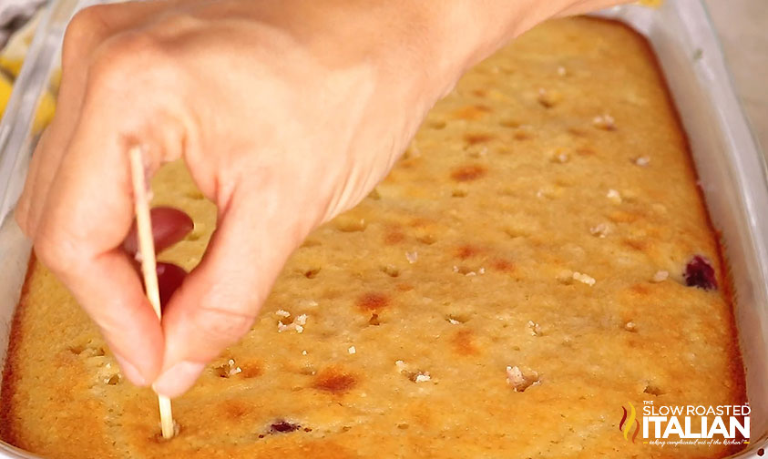 poking holes in top of blueberry poke cake