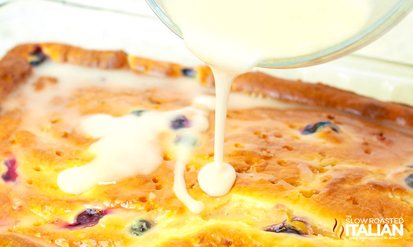 pouring mixture over blueberry poke cake