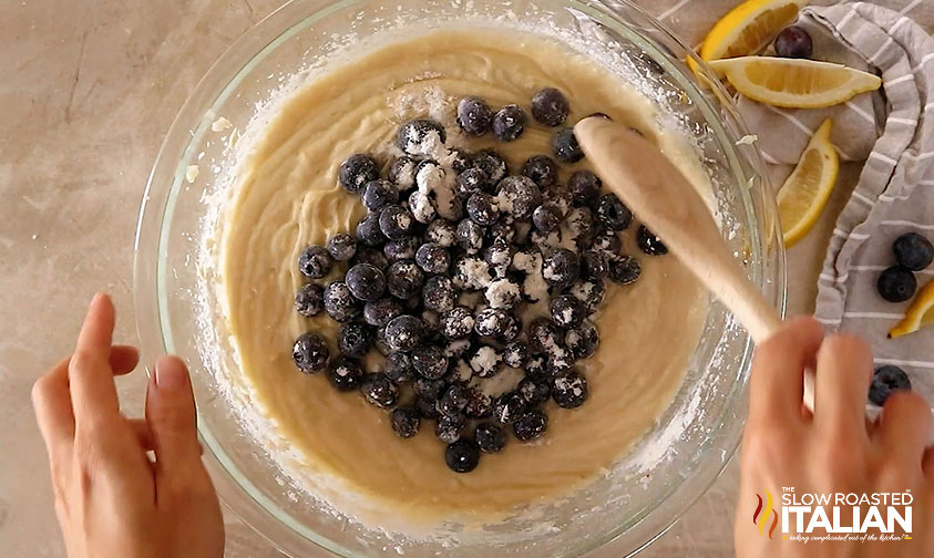 overhead: stirring fresh blueberries into cake batter