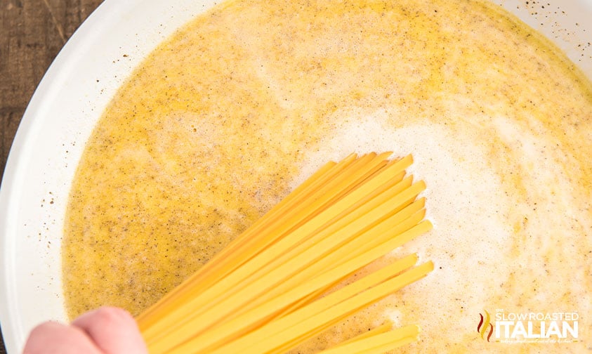 adding linguine to pot of seasoned liquid