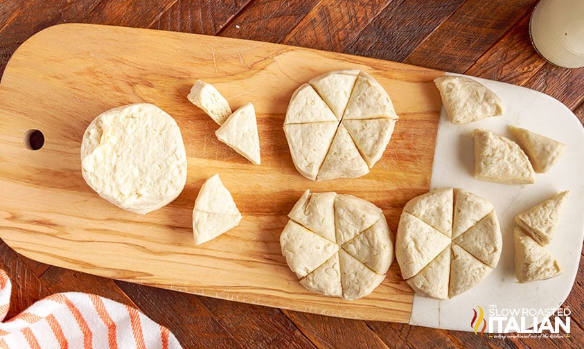 overhead: refrigerated biscuit dough cut into wedges on cutting board