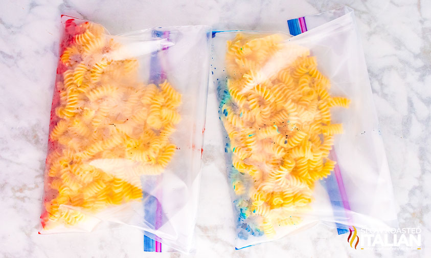 two bags of rotini in Ziploc bags with food coloring