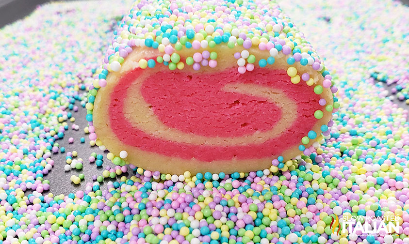 rolling pinwheel cookies dough through sprinkles