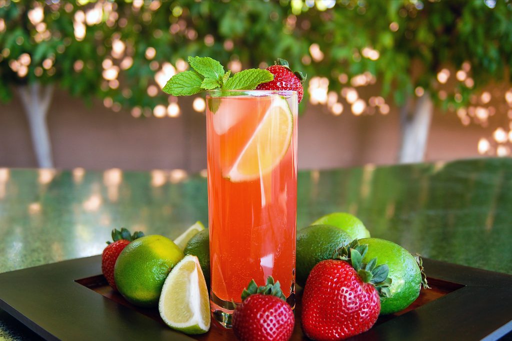 strawberry mojito in tall drinking glass garnished with fresh lime and strawberry