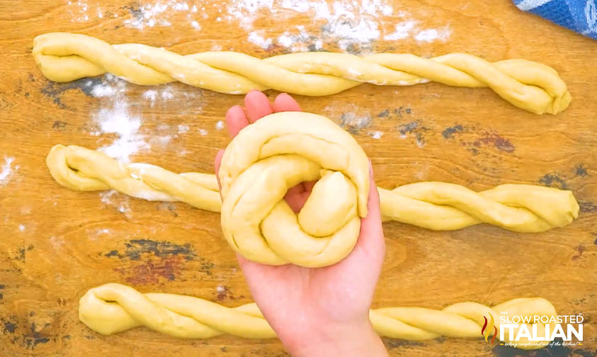 braiding ropes of bread dough on floured wood surface