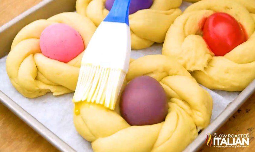 brushing egg wash on italian easter bread before baking