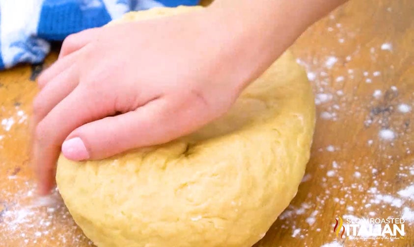 woman's hand kneading batch of dough