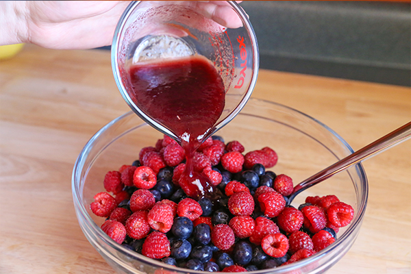 pouring strawberry dressing into bowl of fruit