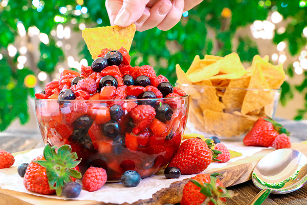 dipping chip into bowl of fruit salsa