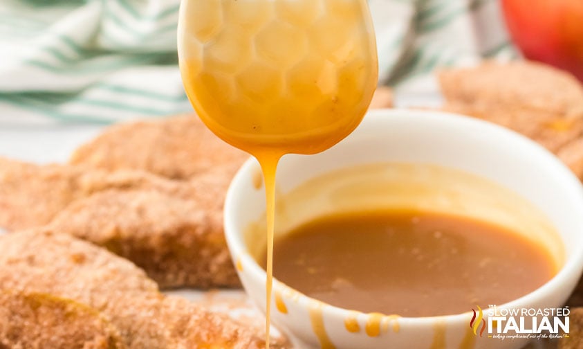 caramel sauce dripping from spoon surrounded by apple fries