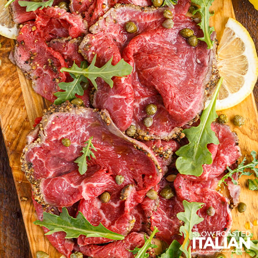 beef carpaccio laid out on wood board