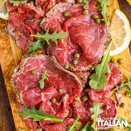 beef carpaccio laid out on wood board