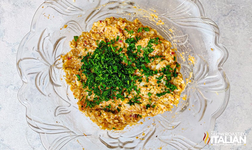 mixed ingredients for cheesy cauliflower bites in glass bowl