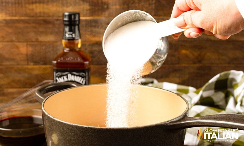 adding sugar to pot of jack daniles bbq sauce