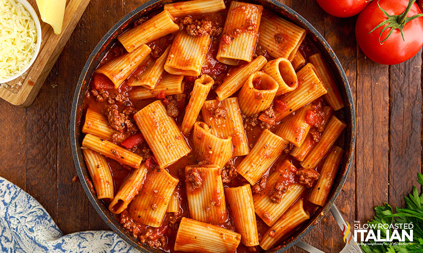 adding pasta to sauce in skillet