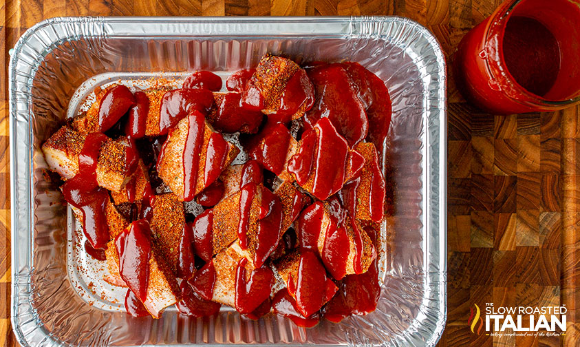 smoked pork belly in aluminum pan covered in bbq sauce