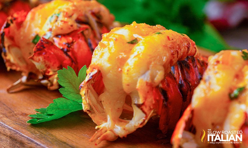 smoked lobster tails close up on wood board with parsley