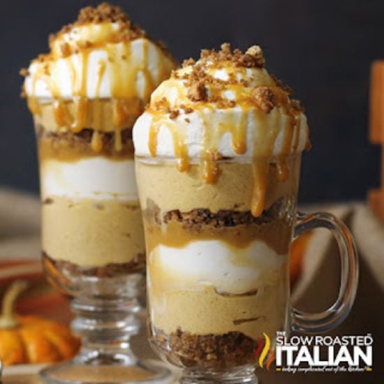 pumpkin parfait in glass mug topped with caramel sauce and cookie crumbs.