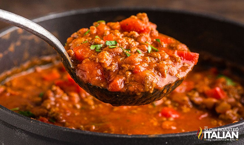 close up of chili with beef and sausage in ladle