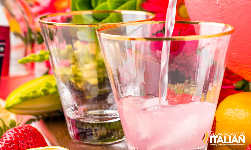 pouring spiked strawberry lemonade into glass