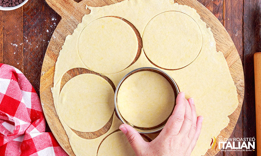 cutting out dough circles for cannoli tubes.