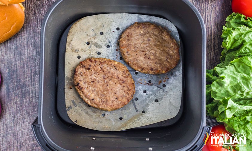 frozen burgers in air fryer basket.