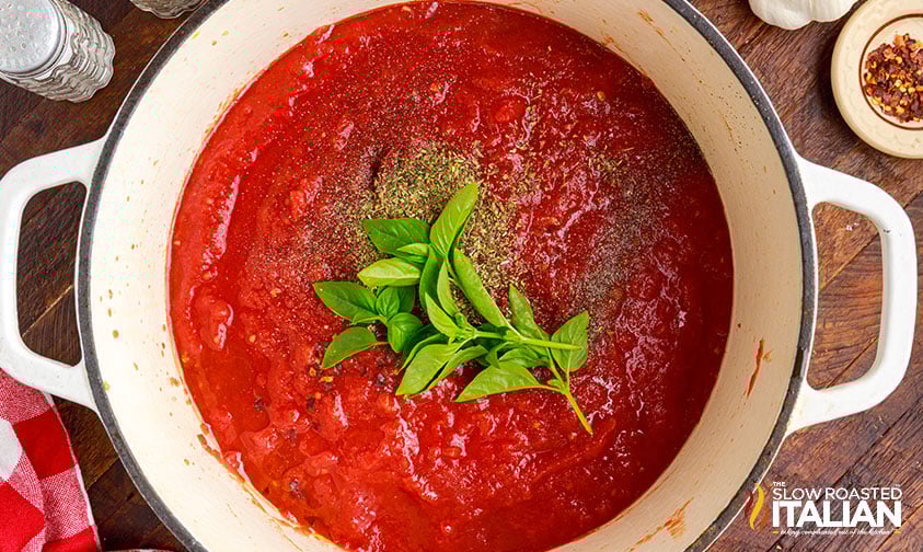 adding basil to marinara sauce.